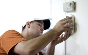 worker installing carbon monoxide detector  